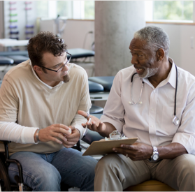 Photograph of a doctor talking to a younger man about information on his medical chart Photograph of a doctor talking to a younger man about information on his medical chart